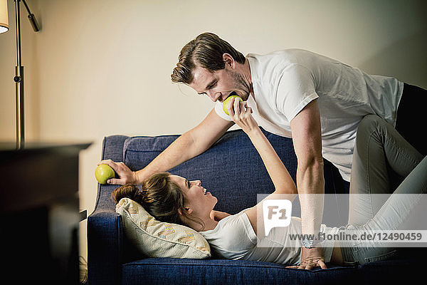 Ein Paar teilt einen Apfel zusammen auf dem Sofa in einem Hotelzimmer