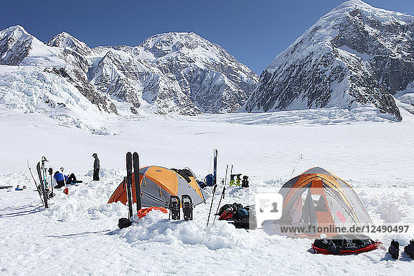 A team of mountaineers is resting in their camp with tents on the lower Kahiltna glacier on their way to Mount McKinley in Alaska. An ascent to the summit of this peak (seen in the background) normally takes three weeks. During this period climbers sleep in tents  cook for themselves and have to melt snow to get drinking water. Mount McKinley or Denali is the highest mountain peak in North America  with a summit elevation of 20 237 feet (6 168 m) above sea level. At some 18 000 feet (5 500 m)  the base-to-peak rise is considered the largest of any mountain situated entirely above sea level. Measured by topographic prominence  it is the third most prominent peak after Mount Everest and Aconcagua. Located in the Alaska Range in the interior of the U.S. state of Alaska  McKinley is the centerpiece of Denali National Park and Preserve. '