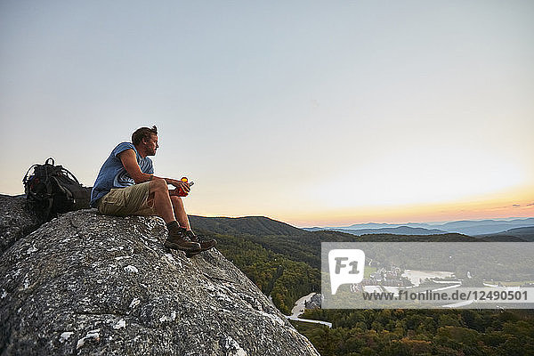 Ein Mann sitzt auf einem Felsen und genießt den Sonnenuntergang entlang des Appalachian Trail