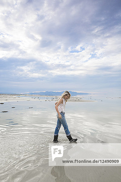 A young woman walks in the desert and the Great Salt Lake of Utah.