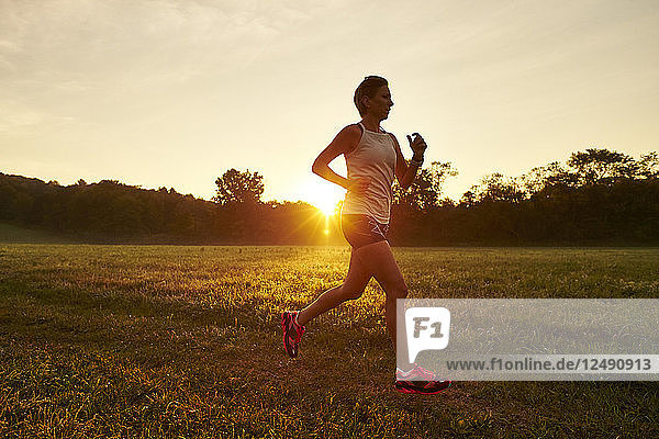 Woman Running On Grassy Field During Sunrise