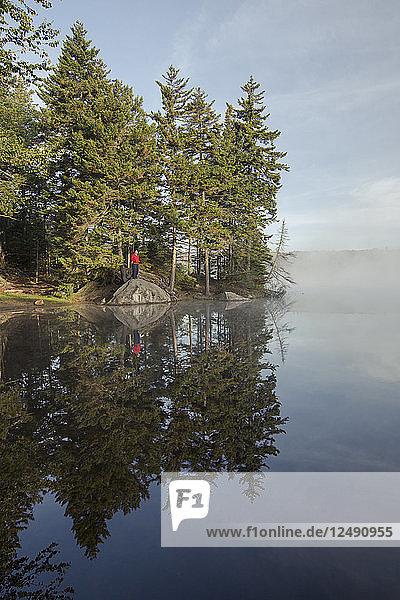 Ein Wanderer genießt den kühlen Morgen an einem See in Vermont