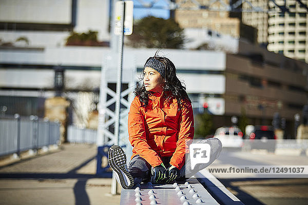 Ein junger asiatischer Läufer/Sportler in einer städtischen Umgebung in Ruhe.