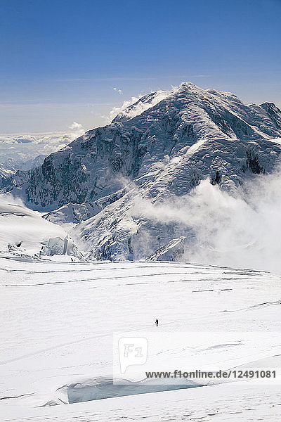 Entfernte Ansicht von Clark Fyans Wandern auf einer verschneiten Landschaft in Alaska.