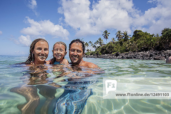 Eine Familie amüsiert sich in der Waimea Bay an der Nordküste von Oahu