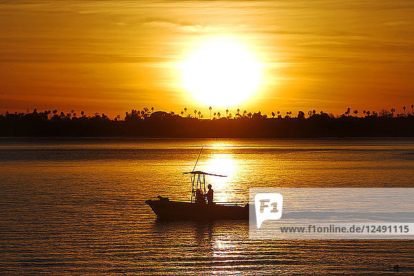 A fishing boat returns to a dock at sunset in Mission Bay in San Diego  CA.
