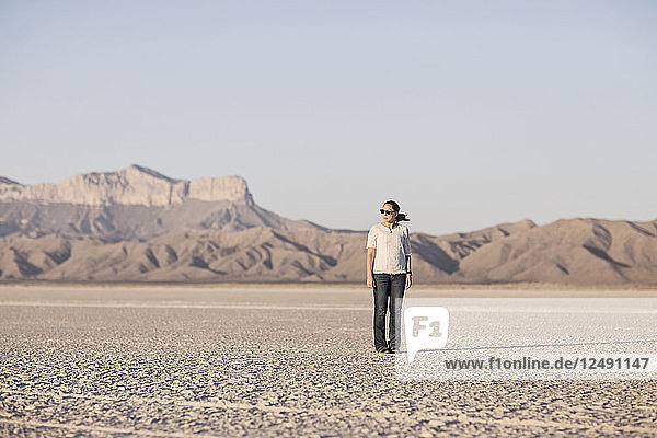 Eine junge Frau  die auf einer Salzebene in Texas mit Guadalupe Peak im Hintergrund steht