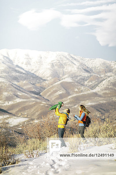 Ein junges Paar und sein Baby wandern in den winterlichen Bergen.