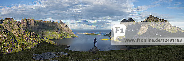 Female hiker takes in panoramic view over Reinefjord and surrounding mountains  near Vindstad  Moskenes??y  Lofoten Islands  Norway