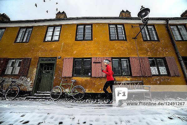Frau joggt vor einem historischen Gebäude in Kopenhagen im Winter