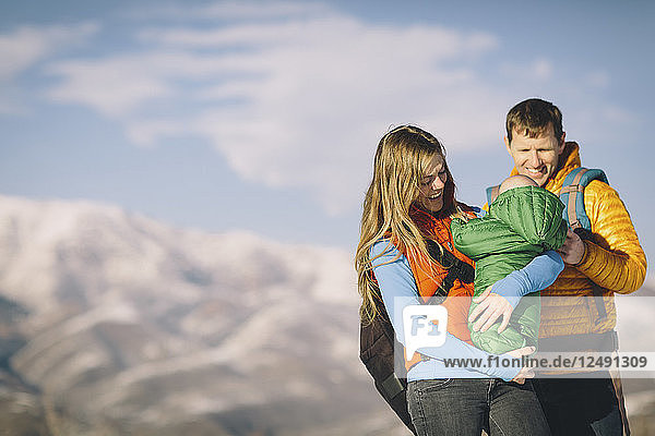A young couple and their baby hike in the wintry mountains.