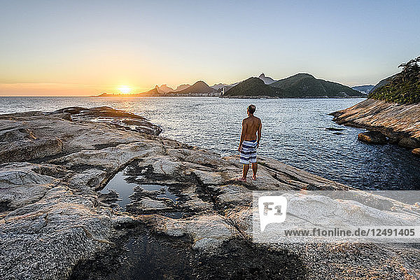 Mann beobachtet den Sonnenuntergang von der Ilha de Cotunduba (Cotunduba-Insel) in Rio de Janeiro  Brasilien