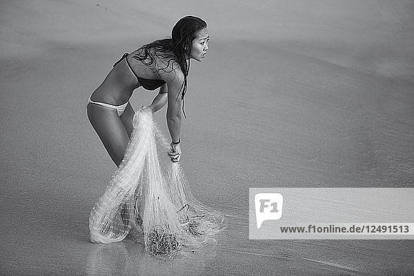 Eine asiatisch-hawaiianische Frau beobachtet die Wellen beim Netzfischen auf Hawaii.