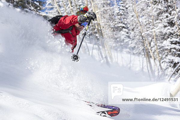 Mann Skifahren bergab in tiefen Pulverschnee auf verschneiten Landschaften