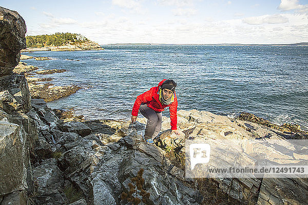 Hiker climbs around sea cliffs in Acadia National Park  Maine