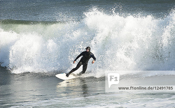 Surfer in wetsuit riding wave