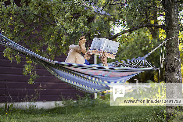 Eine Frau liest ein Buch in ihrer Hängematte auf ihrer Ranch im Sommer in Montana.