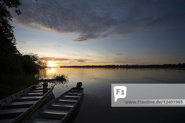 Zwei Boote sitzen bei Sonnenuntergang am Ufer des Amazonas in Peru.