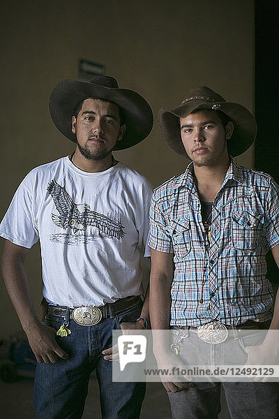 Two young man give pose in cowboy hat.