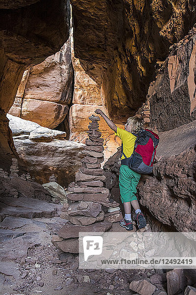 A young girl backpacking past stone cairns on the Joint Trail in the Needles District of Canyonlands National Park  Monticello  Utah.