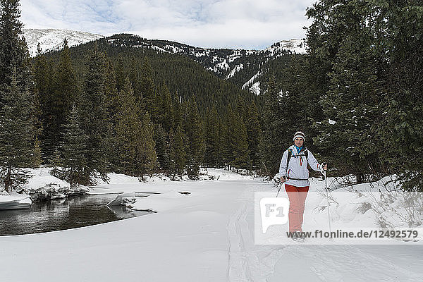 Frau auf Schneeschuhen durch verschneiten Wald  Berge