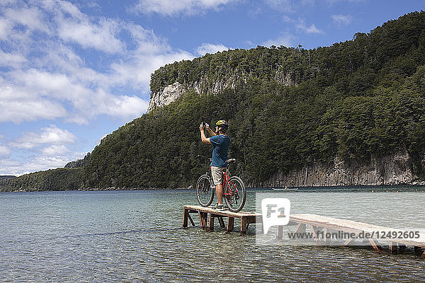 Fahrradfahrer macht Foto auf kleinem Steg am Bergsee