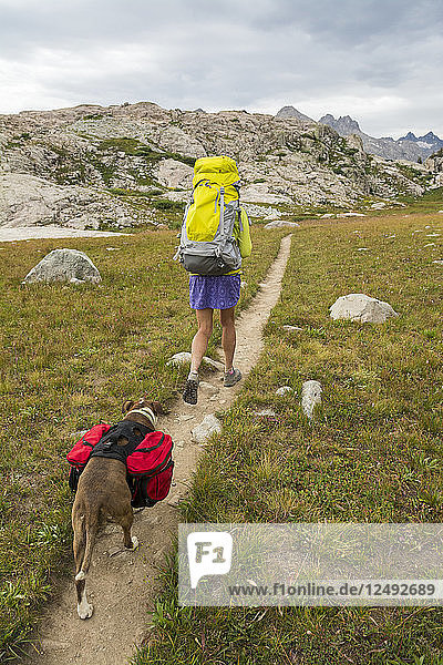 A woman and her dog hiking along trail into Titcomb Basin in the Wind River Range  Bridger Teton National Forest  Pinedale  Wyoming.