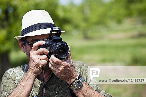 A Japanese American man takes a picture with a DSLR camera.