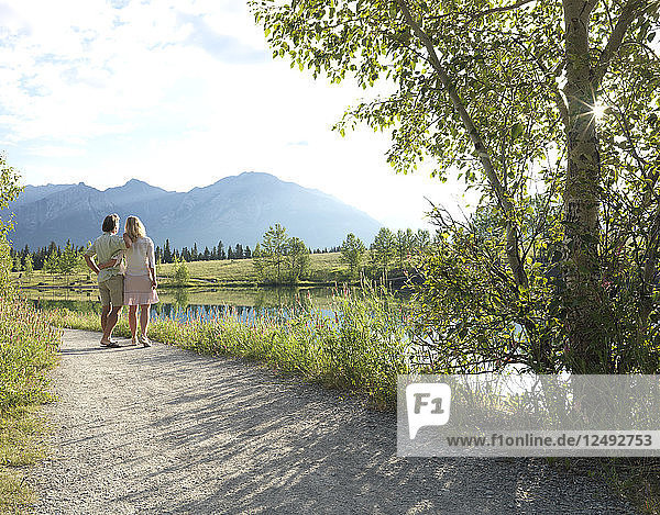Couple walk along trail by mountain lake