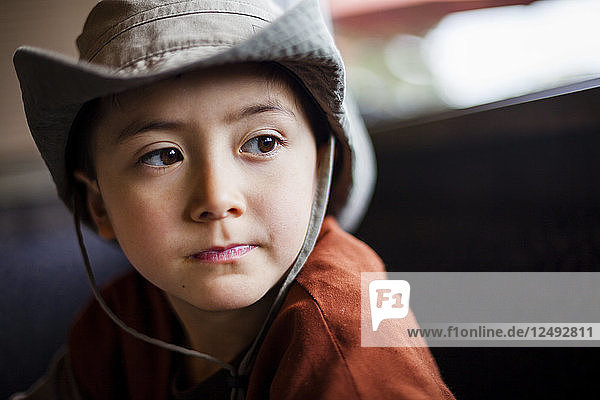 A 6 year old Japanese American boy looks pensive.