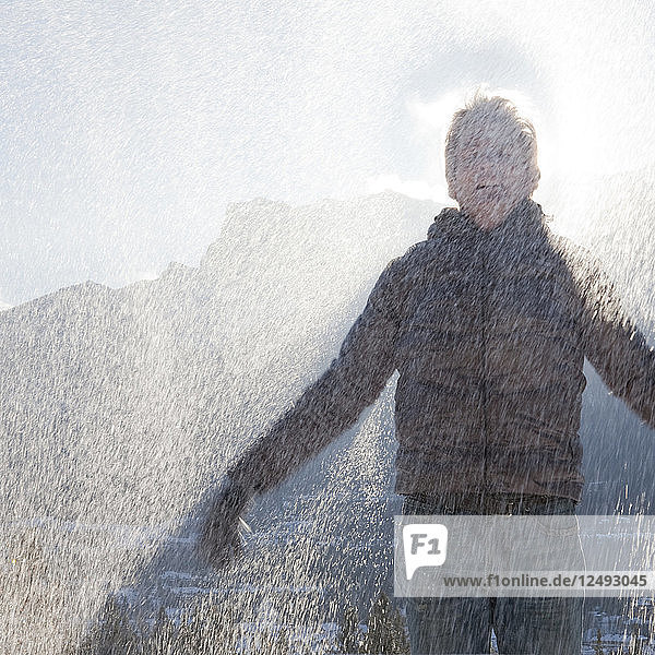 Mann feiert in den Bergen  während Schneekristalle fallen