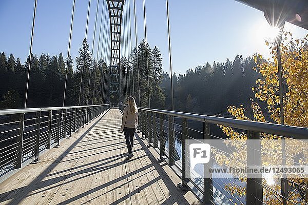 Woman walks over bridge  autumn forest  lake