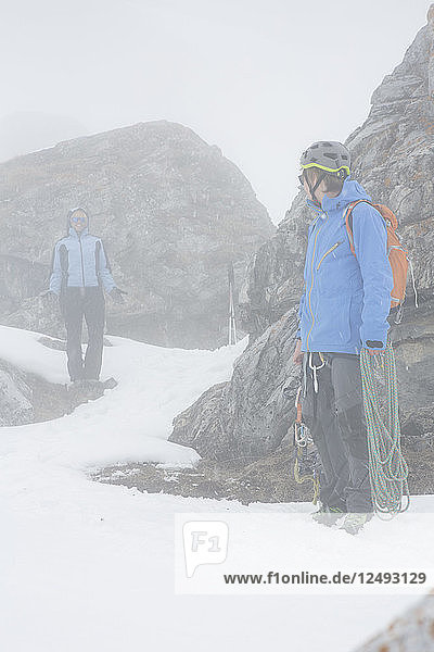 Zwei Bergsteiger klettern im Nebel auf Felsen