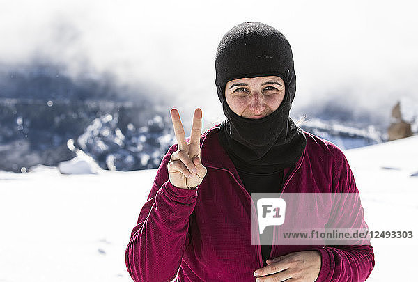 Porträt einer Snowboarderin mit Friedenszeichen am Cerro Catedral