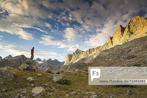 A woman standing on rock watching sunset in Titcomb Basin in the Wind River Range  Bridger Teton National Forest  Pinedale  Wyoming.