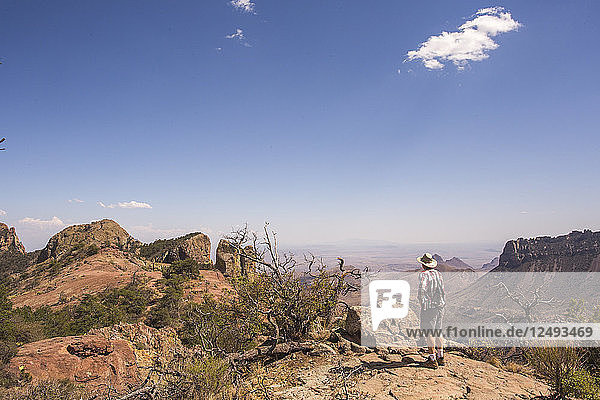 Ein Mann  der auf einem Felsen steht und die Wüstenlandschaft erkundet