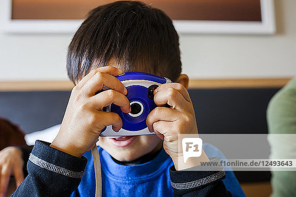 A 4 year old Japanese American boy takes a picture with his toy camera.