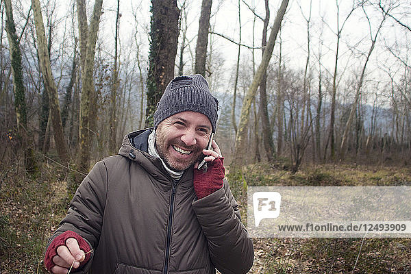 The Happy Young Man Talking Over The Phone While Walking In The Forest