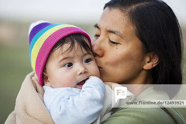 Eine japanisch-amerikanische Frau umarmt und küsst ihr 6 Monate altes Mädchen während eines Campingausflugs in den Badlands  South Dakota.