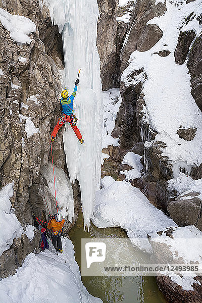 A man and woman ice climbing a frozen waterfall in the Ouray Ice Park  Ouray  Colorado.