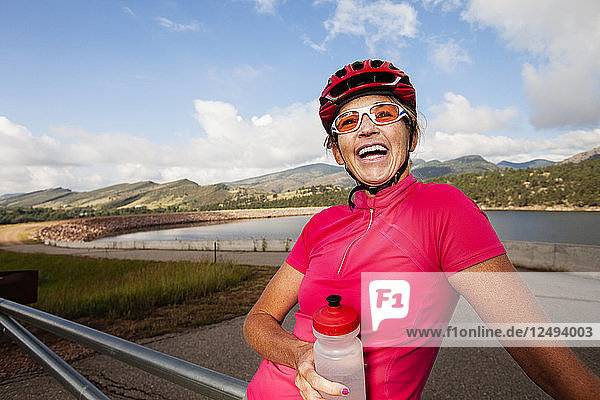 Eine Rennradfahrerin macht auf der N Co Rd 29 am südlichen Ende des Green Ridge Glad Reservoir eine Pause  um ihr Rennrad zu fahren. Sie hydratisiert mit ihrer Wasserflasche.