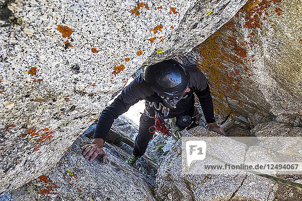 Ein Mann quetscht sich durch ein Loch in den Felsen auf einer Kletterroute in Utahs Wasatch Mountains