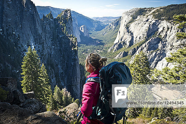 A female backpacker stops to take in the views of Yosemite National Park on a sunny day.