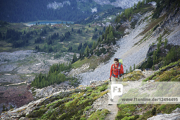 Woman hikes to the views of Glacier Peak Wilderness from Spider Gap on the Phelps Creek Trail  14.2-mile out-and-back  outside of Leavenworth  Washington September 2011. Phelps Creek leads to the base of Spider Glacier where you setup camp and hike to 7 100-foot Spider Gap. Camp has a bald eagle view of Spider Meadow below and craggy Seven Fingered Jack in the distance.