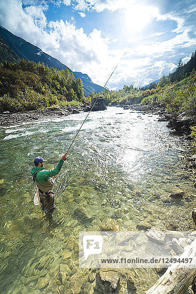 A man fly fishes in the clear waters of Revelstoke  British Columbia  Canada.