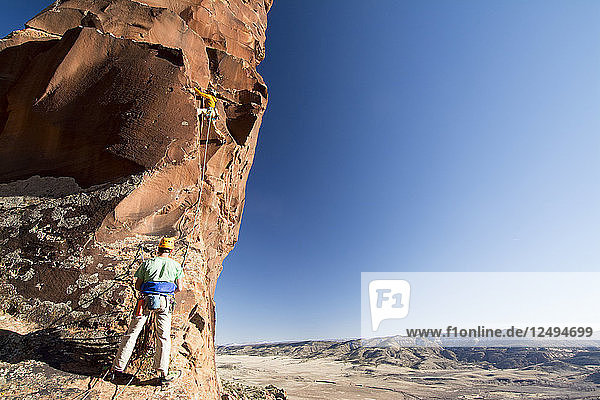 A man and woman rock climbing a route called Psycho Path on Psycho Tower above the Big Gypsum Valley  Naturita  Colorado.