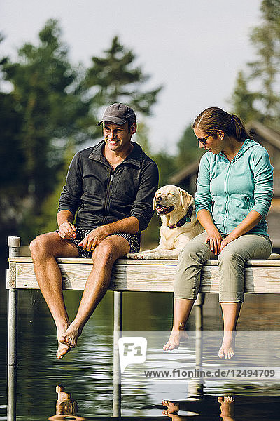 Mann und Frau mit ihrem Hund sitzen am Rande des Docks auf Kaspischen See