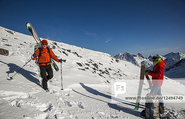 Skifahrer fahren während der Spearhead Traverse in den Coast Mountains von British Columbia  Kanada  einen Schneehang voller Felsen hinunter.
