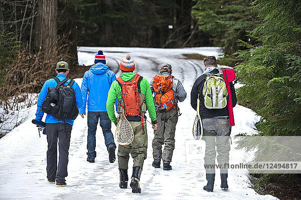 Eine Gruppe von Freunden in Angelausrüstung geht eine Bergstraße in Squamish  British Columbia  hinunter.