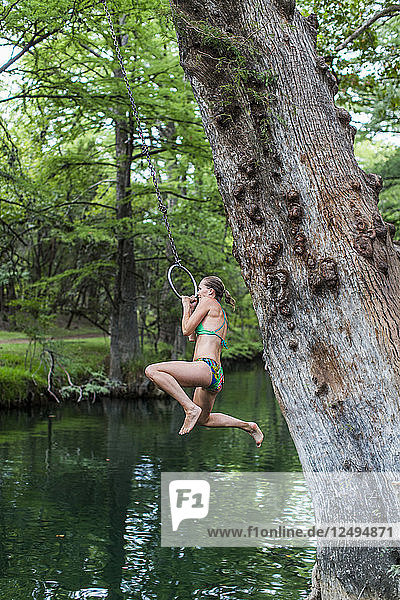 A young girl enjoys a rope swing at the Blue Hole in Wimberley  Texas is a popular destination for tourists and locals on hot summer days. The clear  cool water flows through cypress trees and offers a refuge from the Texas heat.
